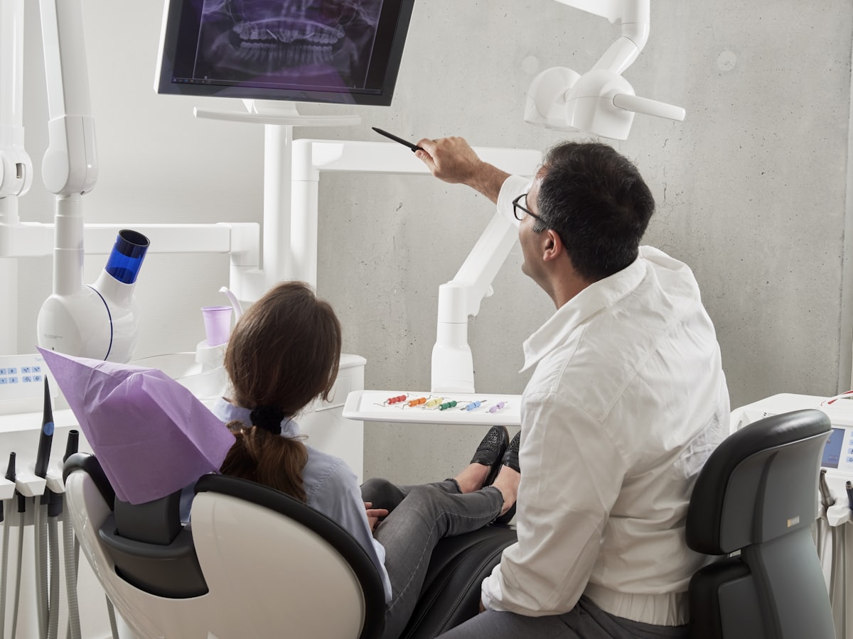 A dentist pointing out findings on a panoramic X-ray to a seated patient